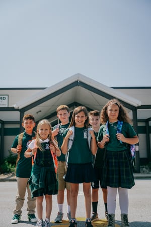 Group of students smiling in front of school